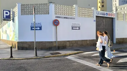 Dos mujeres cruzan por el paseo de peatones delante del señalizado y rotulado Parking Salesianas