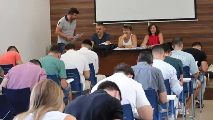 Diferentes personas que aspiran a ser policías locales de Chiclana sentados/as en un salón realizando un examen.