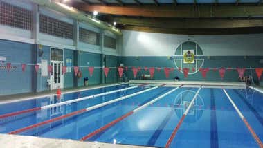 Piscina con las calles marcadas por boyas y banderines sobre el ancho de la misma.