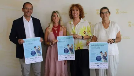 Isabel Butrón, en el centro, con vestido rosa y rojo, con el cartel en la mano en la presentación del torneo.