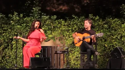 Imagen de Rosalía cantando en directo en 2016, con gesto concentrado y luz cálida sobre el escenario del Real Alcázar de Sevilla, durante su interpretación del tango gaditano 'Los duros antiguos'.