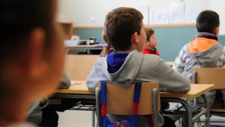 Niños y niñas atendiendo al profesor en el colegio.