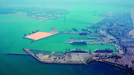 Vista del mar azul con el puente al fondo y la zona portuaria en primer término.