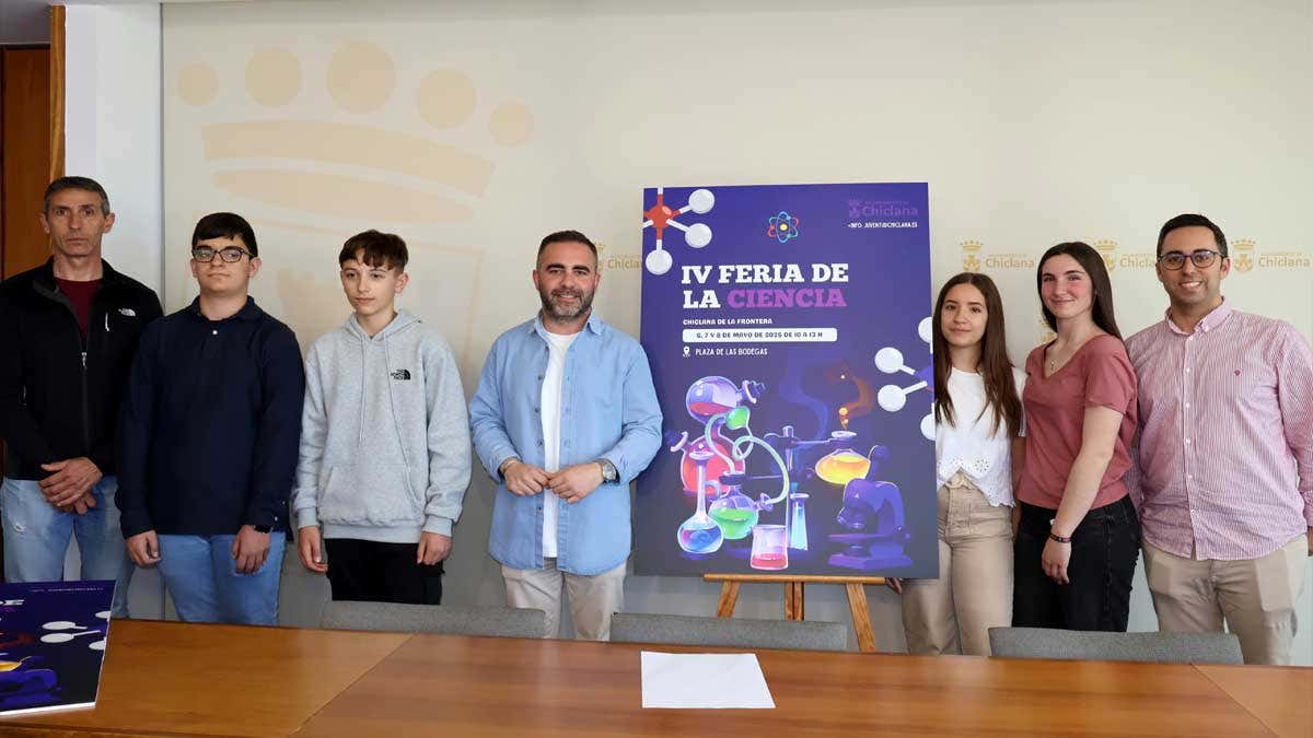Alumnos y delegado de Cultura de Chiclana junto al cartel de la IV Feria de la Ciencia.