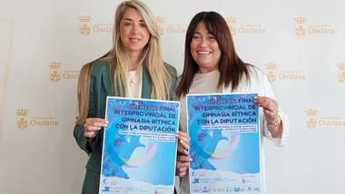 Isabel Butrón junto a Silvia Castillo sostienen el cartel de la Final Interprovincial de Gimnasia Rítmica en Chiclana destacan este por sus tonos celestes.