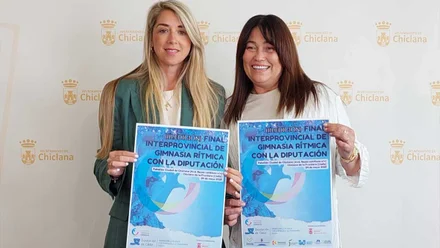 Isabel Butrón junto a Silvia Castillo sostienen el cartel de la Final Interprovincial de Gimnasia Rítmica en Chiclana destacan este por sus tonos celestes.