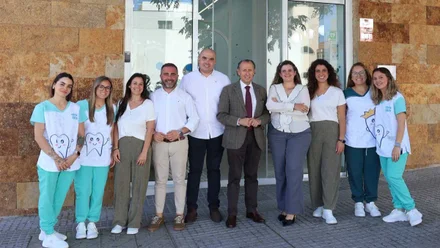 Alcalde y empleados delante de la fachada del Centro Dental Infantil Ávila Bobillo, destacan los tonos tierra y la indumentaria blanca y verde de los empleados.