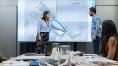 La alcaldesa de San Fernando, Patricia Cavada, con blusa celeste, delante de una pantalla de televisión con el proyecto del estadio.