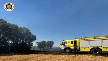 Camión amarillo de bomberos en un pastizal en tareas de extinción del incendio.