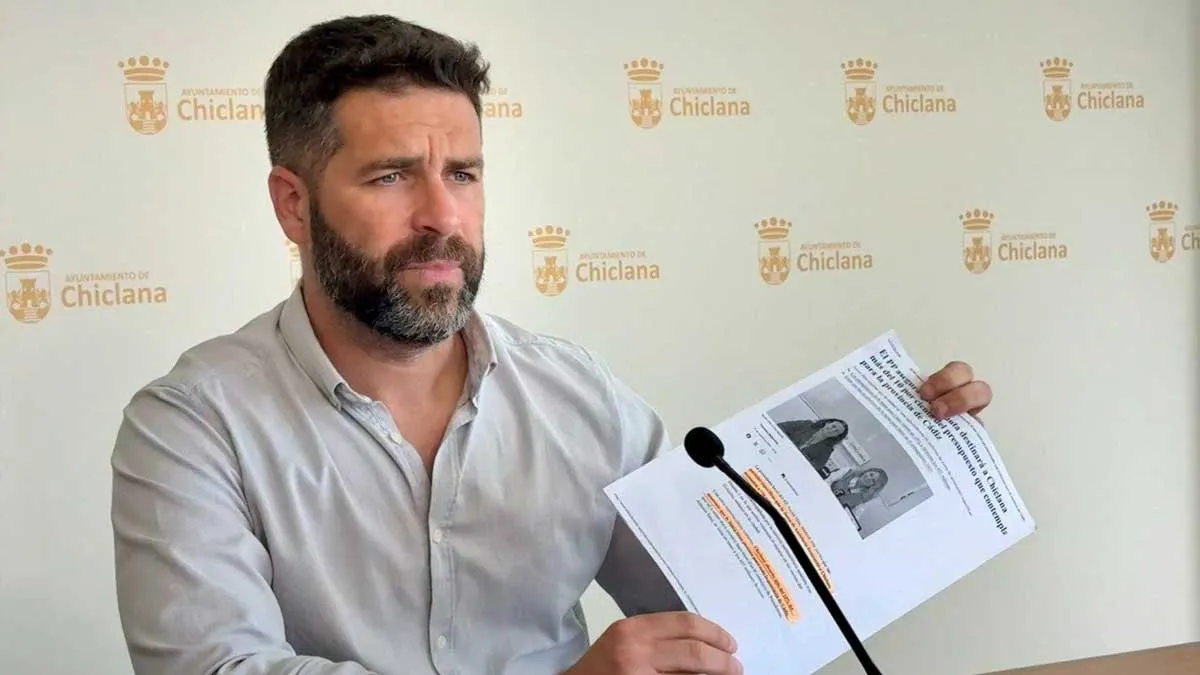 Roberto Palmero, con camisa clara, muestra un documento en las manos.