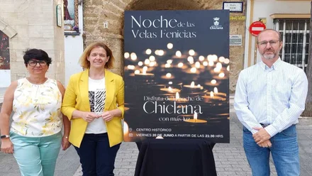 Representante municipal y organizadores junto al cartel, negro con velas amarillas, de "La noche de las velas fenicias" de Chiclana.