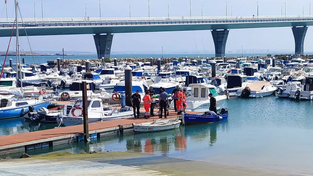 Momento en el que la mujer rescatada del agua es llevada en una camilla en el Club Náutico Viento de Levante de Cádiz