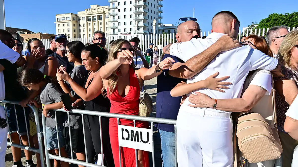 Lagrimas en un lado, abrazos en el otro y brazos abiertos de una mujer esperando a un guardiamarina.