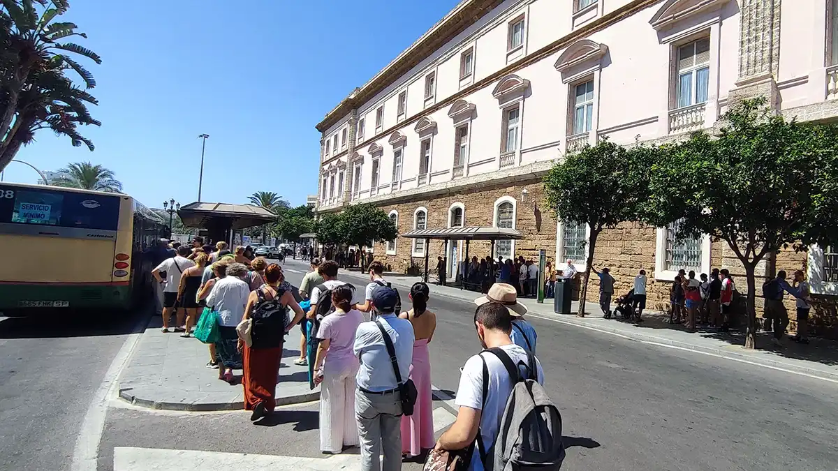 Cola a pleno sol en la Plaza de España para subir a un autobús en la octava jornada de huelga