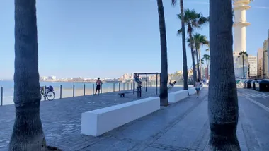 Un grupo de personas hacen ejercicio en la zona deportiva sobre Santa María del Mar con el cielo azul y completamente despejado y la Catedral de Cádiz al fondo