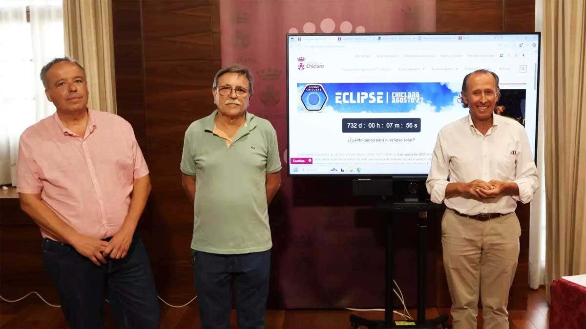 José María Román, alcalde de Chiclana, junto a los dos expertos y, tras ellos, una pantalla explicativa.