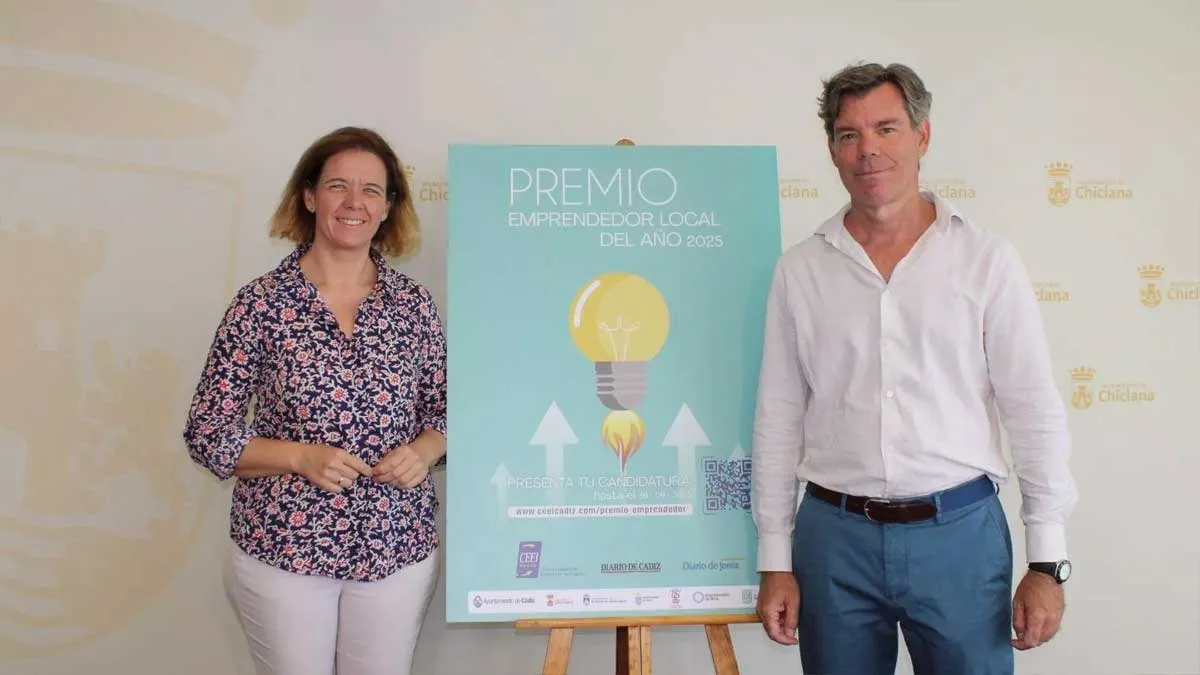 Manuel Pérez, con camisa estampada y Sánchez-Cossio, con camisa blanca, junto al cartel que está en el centro en tono turquesa.