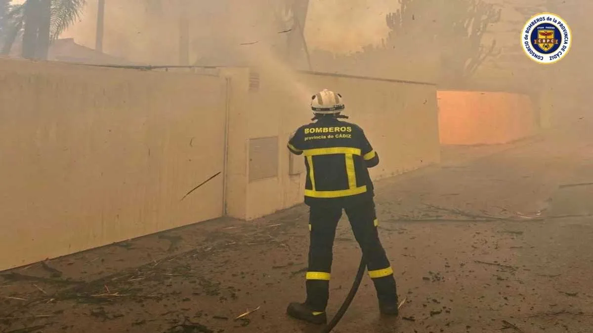 Bombero, de azul, con la manguera apagando el incendio.
