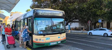 Varias personas suben al autobús de la línea 2 en la parada de La Caleta durante la huelga de autobuses con un taxi al fondo en la parada