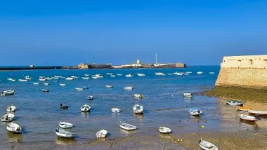 Imagen de la playa de la Caleta, con Santa Catalina en primer plano, San Sebastián al fondo y el mar en calma antes del regreso del Levante