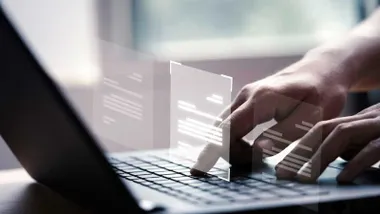 Persona delante de un ordenador portátil tecleando.