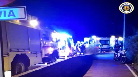 Camión de bomberos, en color amarillo y con las luces en azul junto al arcén.