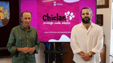 José María Román delante de una pantalla en tonos rosas con el acuerdo por los animales.