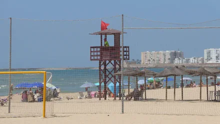 Torre de socorrismo conla bandera roja junto a una de las zonas deportivas de la playa de la Victoria.