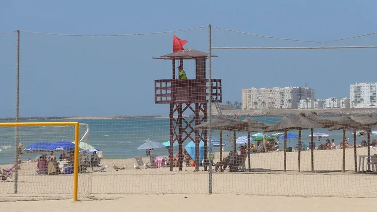 Torre de socorrismo conla bandera roja junto a una de las zonas deportivas de la playa de la Victoria.