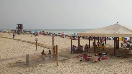 Bandera amarilla en una de las torres de vigilancia de la Playa Victoria con mucho público en la playa.