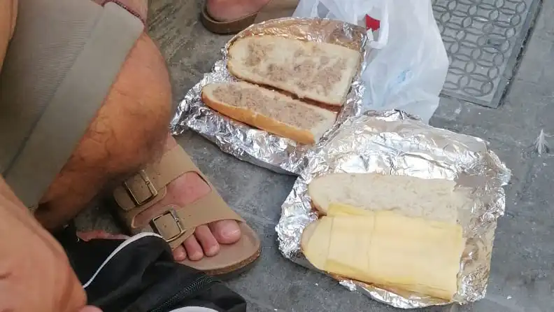 Una persona sin hogar muestra los bocadillos que estan recibiendo, el pasado jueves en la calle Maria Arteaga.