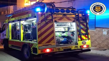 Camión de bomberos, el rojo y amarillo, con las luces azules encendidas.