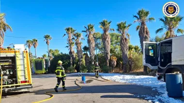 Varios bomberos esparcen espuma sobre el líquido inflamable en la carretera.