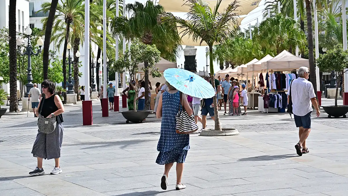 Una mujer camina con un parasol por la plaza de San Juan de Dios de Cádiz.