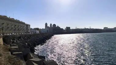 Vista de la Catedral de Cádiz desde el Campo del Sur, con el sol reflejado en el agua y un ambiente que anticipa jornadas de mucho calor