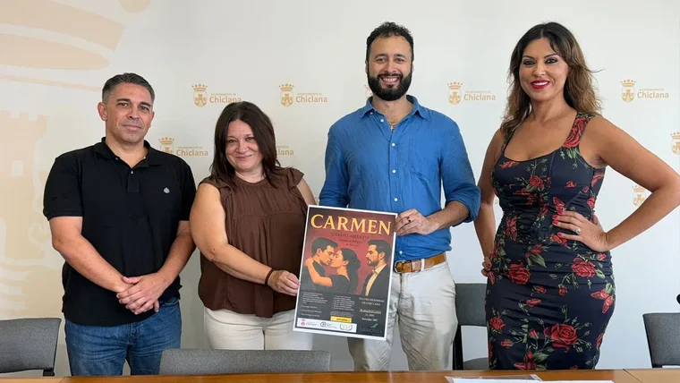 Susana Rivas, de marrón, sostiene el cartel de la ópera Carmen junto a otras tres personas.