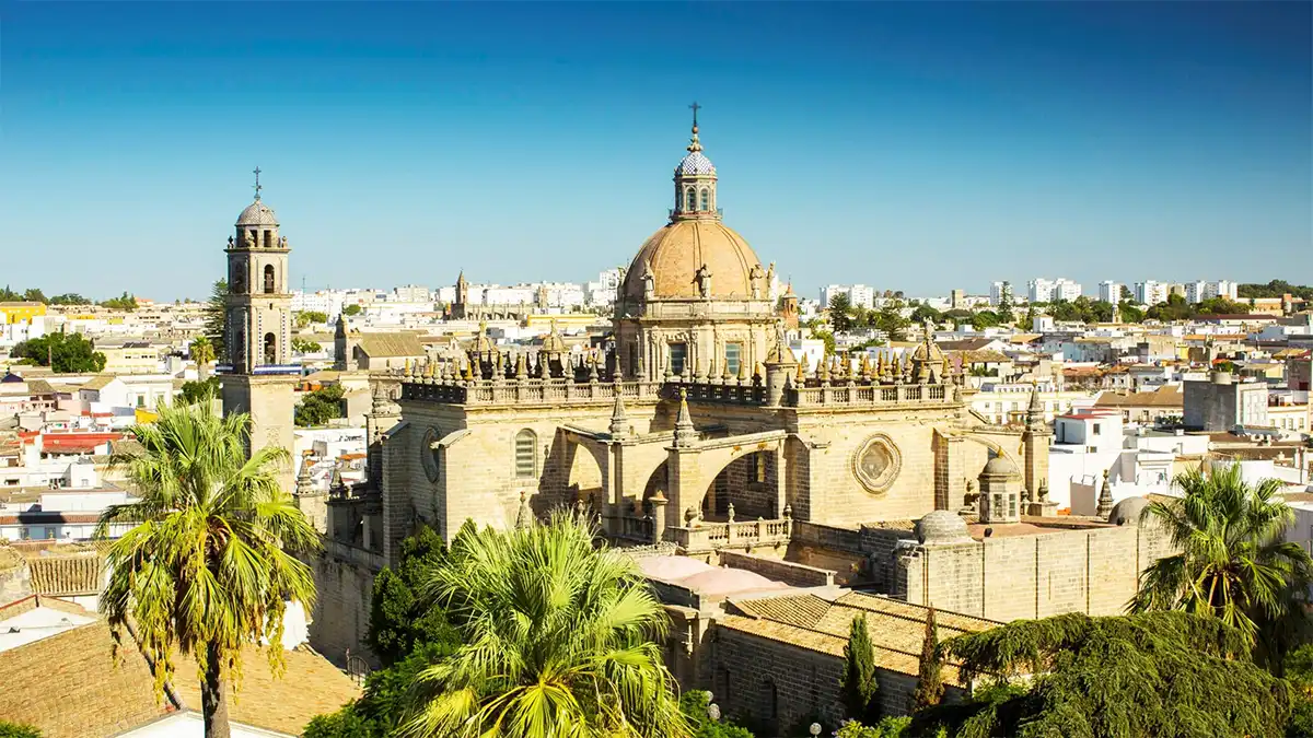 Fotografía tomada desde un punto elevado de Jerez de la Frontera en la que se aprecia una panorámica de la ciudad. En el centro de la imagen destaca la catedral, con su cúpula y torre, rodeada por el entramado urbano. El cielo aparece despejado y luminoso, reflejando la jornada de calor extremo.
