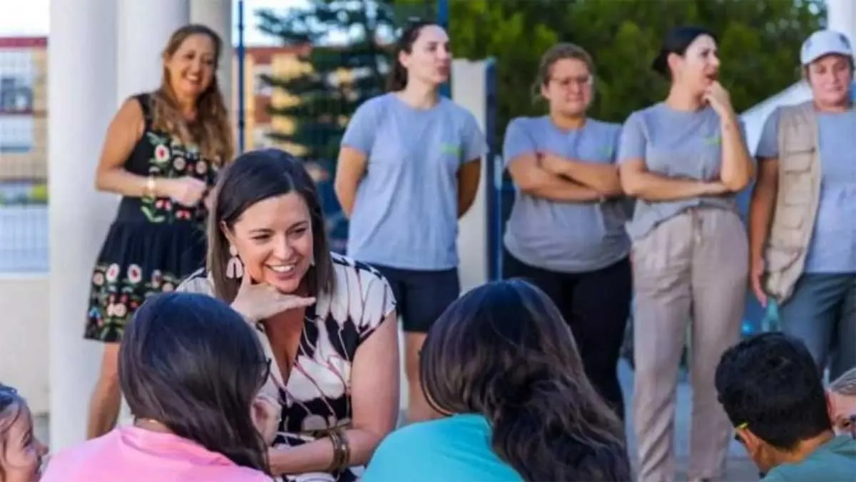 La alcaldesa, Patricia Cavada, agachada, con un vestido estampado, hablando con los niños y niñas.