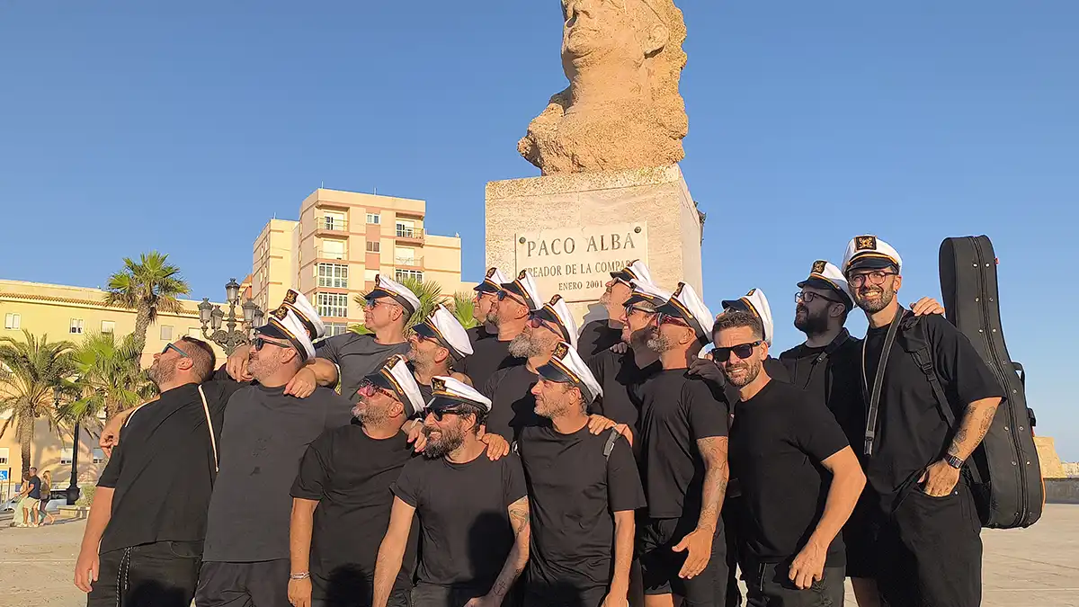 La chirigota de vera Luque posa con gorra marinera al estilo Paco Alba ante su busto antes de interpretar la copla de Currusquillos Gaditanos.