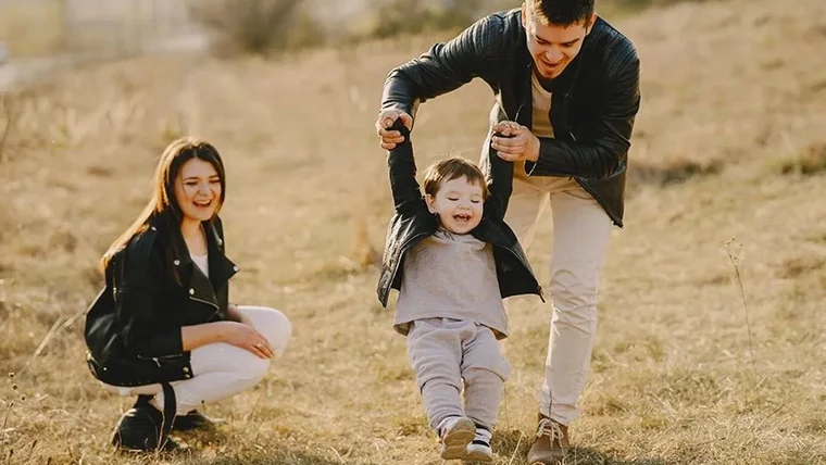 Una familia disfrutando con un niño sobre un campo dorado.