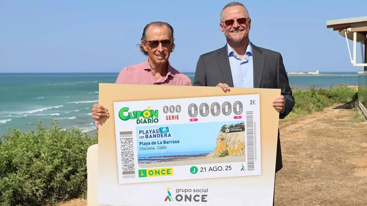 José María Román, alcalde de Chiclana, y el representante de la ONCE, sostienen el cupón gigante de La Barrosa en las manos.