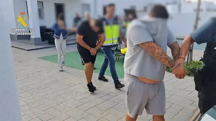 Agentes de la Guardia Civil escoltan a dos hombres y una mujer detenidos en Chiclana de la Frontera, acusados de robar en viviendas de ancianos haciéndose pasar por técnicos de teleasistencia. La imagen muestra a los tres arrestados, acompañados por los guardias civiles durante la operación