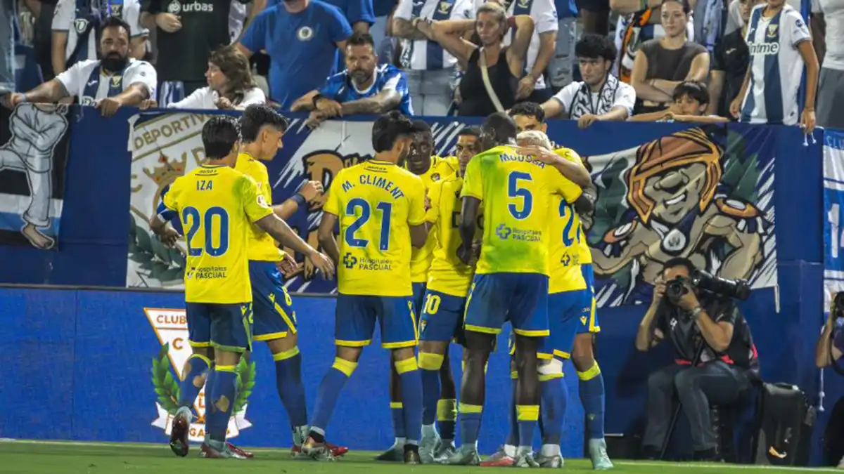 Jugadores del Cádiz vistiendo de amarillo con manchas verdes visibles en la camiseta.