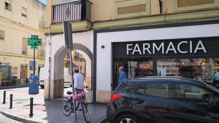 Termómetro digital en la fachada de una farmacia en la calle de La Rosa de Cádiz, con la pantalla iluminada marcando 38 grados a plena luz del día.