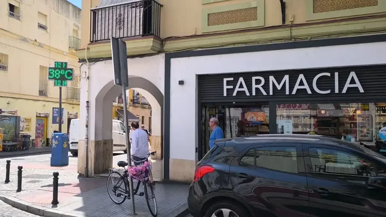 Termómetro digital en la fachada de una farmacia en la calle de La Rosa de Cádiz, con la pantalla iluminada marcando 38 grados a plena luz del día.