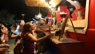 Clientes en uno de los puestos de comida en Rota, destacan los tonos cálidos, rojizos.
