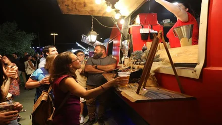 Clientes en uno de los puestos de comida en Rota, destacan los tonos cálidos, rojizos.