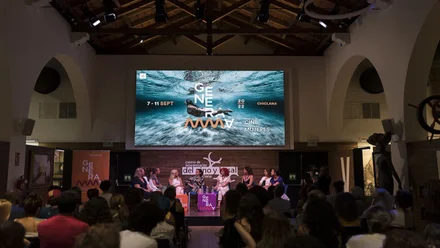 Salón con proyección de pantalla con cartel de Generamma en Chiclana, 2025.