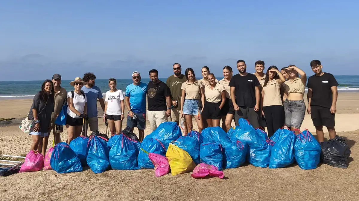 Foto del grupo que acometió la limpieza en Chipiona con la basura recogida.