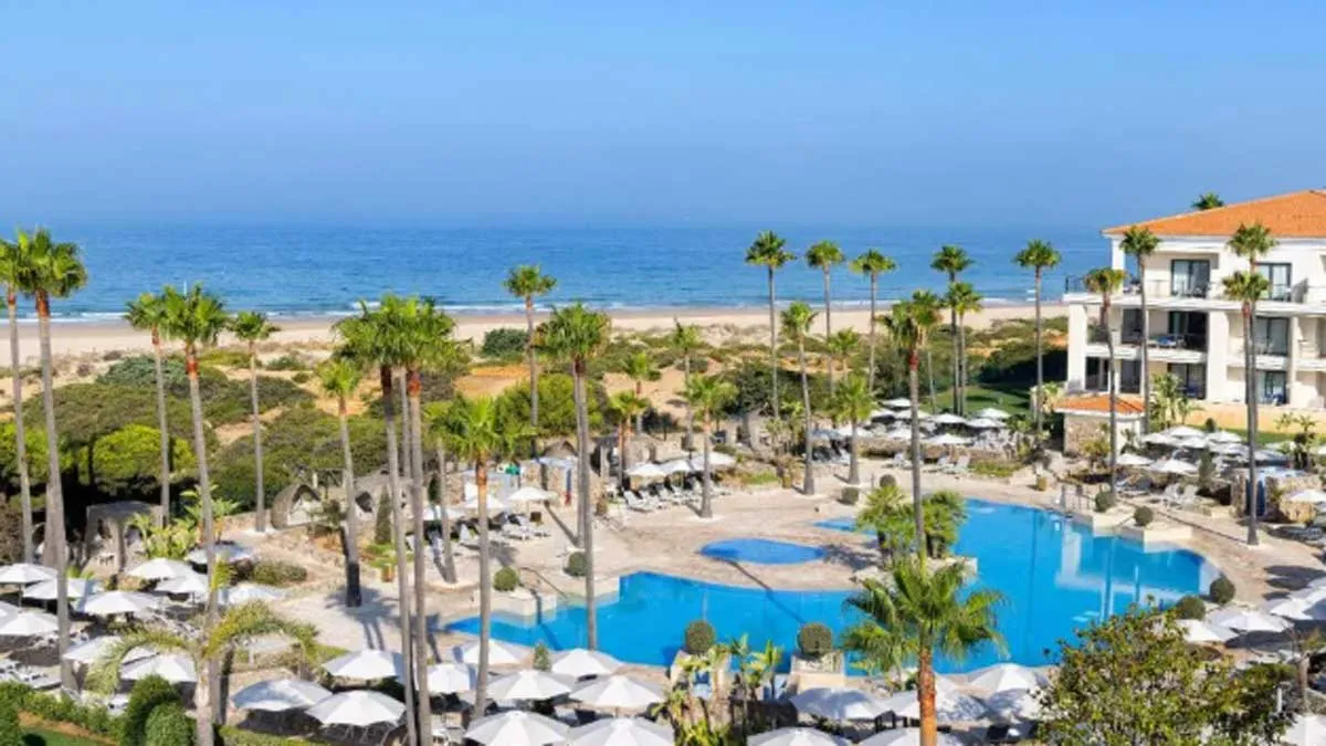 Hotel en Chiclana con la piscina y la playa a la vista.